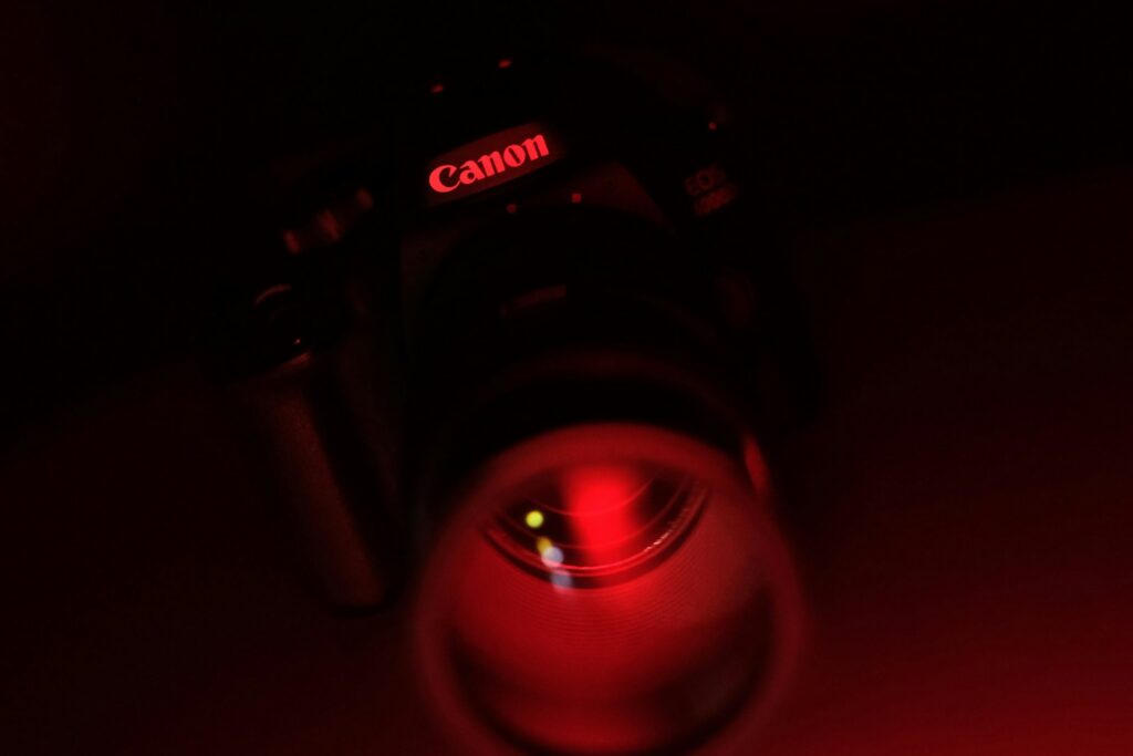 A camera in a dark room, its lens glowing with a red recording light.